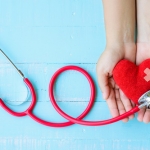 woman-hand-holding-red-heart-with-stethoscope-blue-wooden-background_53476-356
