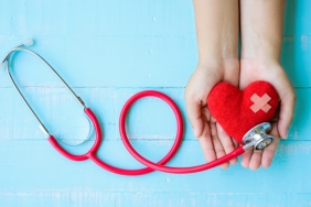woman-hand-holding-red-heart-with-stethoscope-blue-wooden-background_53476-356